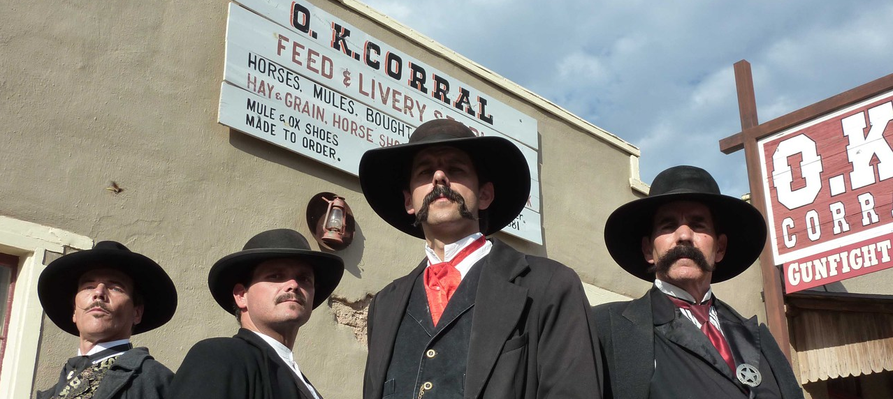 Four gunmen, dressed in black, standing in front of the OK Corral