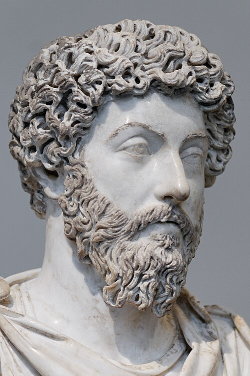 Marble bust of a man with curly hair and a beard, depicting a thoughtful expression.
