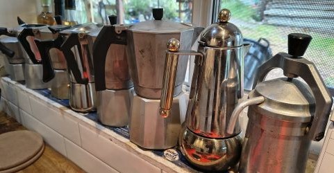 A line of different Moka pots in the kitchen window